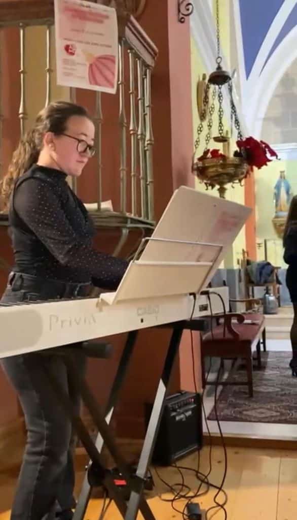 Mujer adolescente tocando el órgano en la iglesia durante el concierto de villancicos